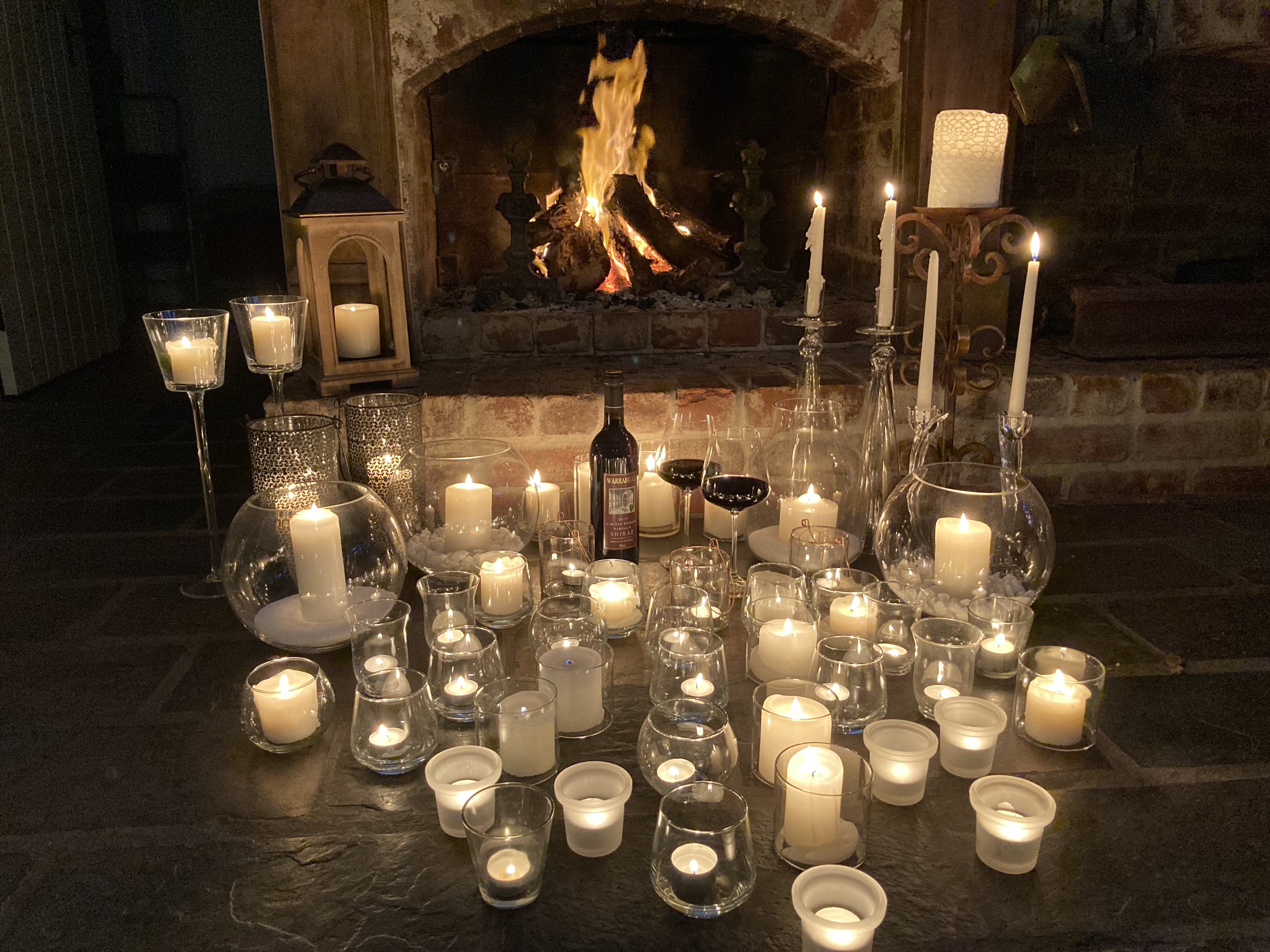 Lots of candles in front of a fireplace